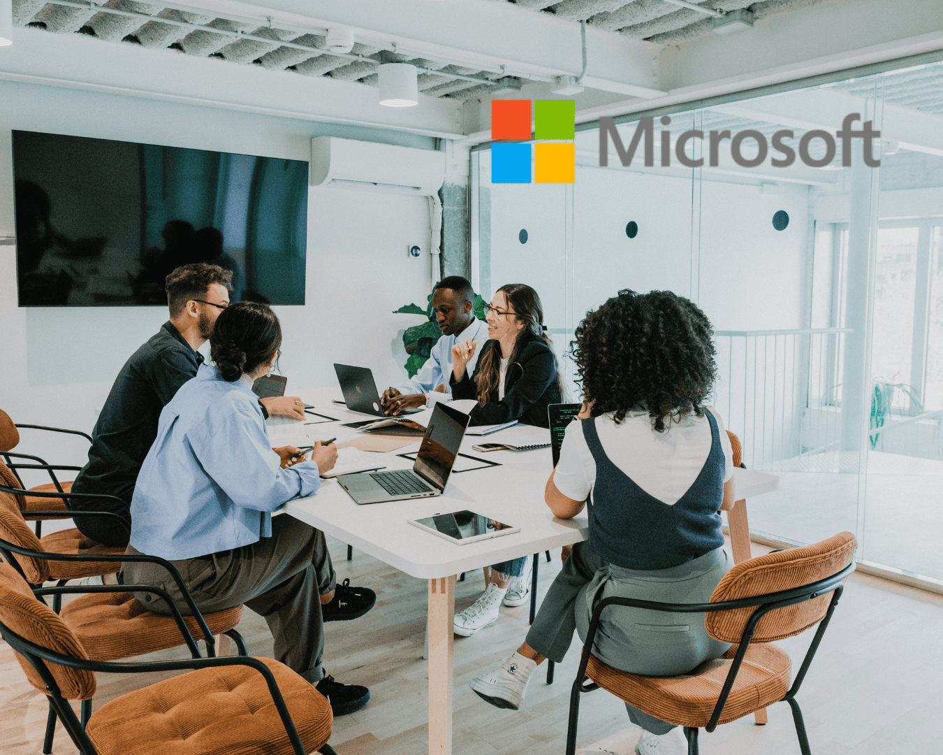 A productive team of diverse employees in a conference room have just made the decision to get private group training on Microsoft AI solutions from SAVAGE AI. The Microsoft logo is also visible.
